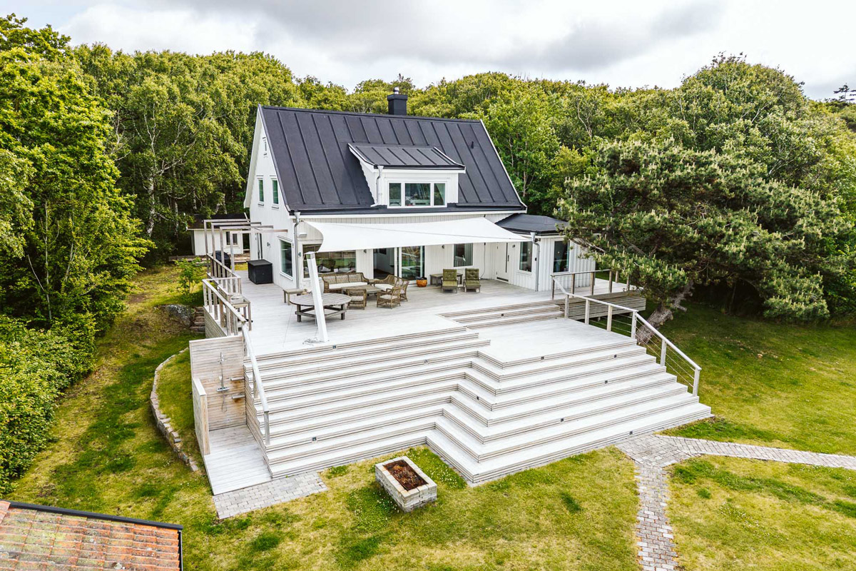 En vit villa med ett stort nylagt trädäck framför