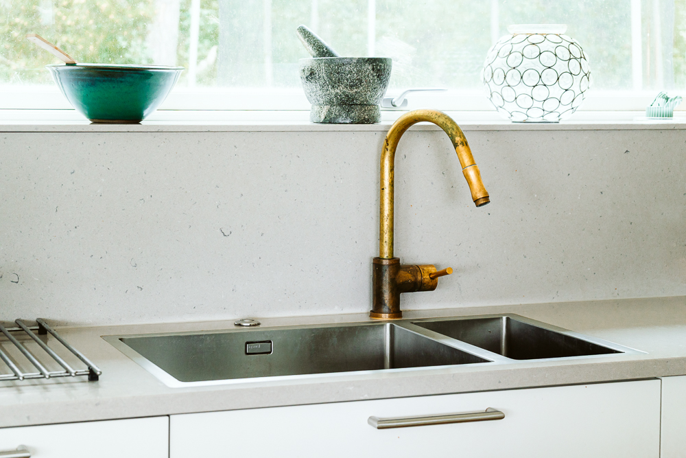En guldkran över en diskho i rostfritt stål