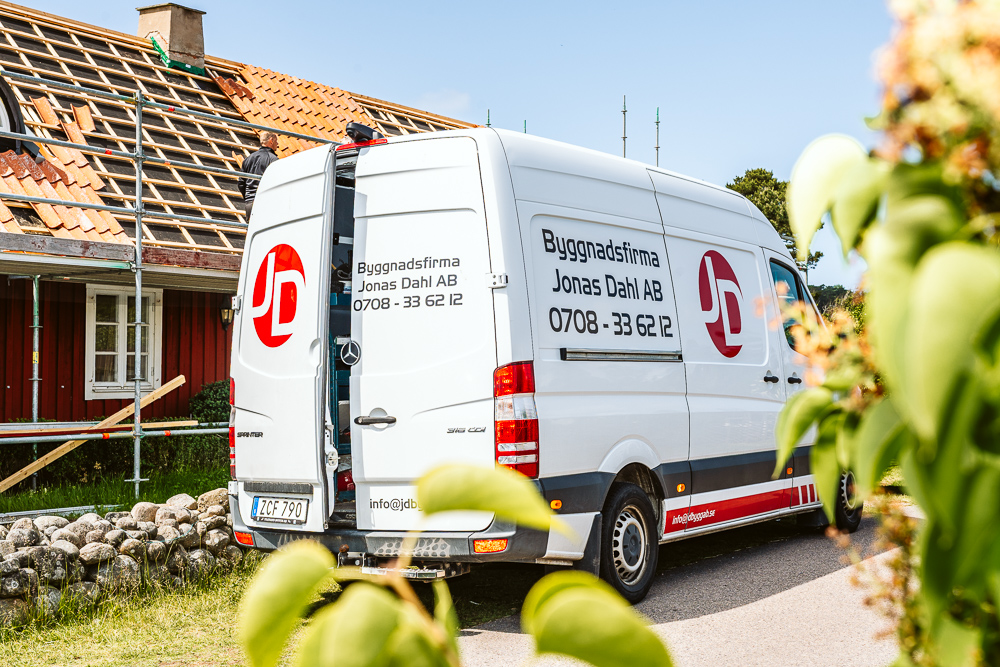 Byggfirma Jonas Dahls firmabil framför en röd villa